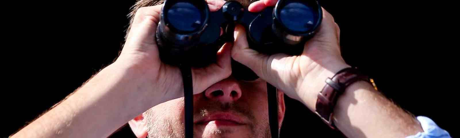 Man watching live horse racing with binoculars
