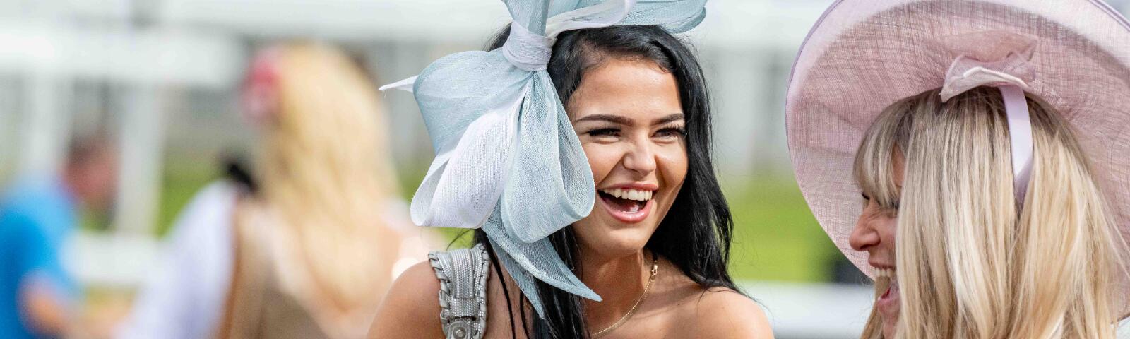 Two race goers at Fontwell races laughing with each other