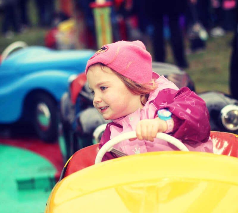 A child sitting in a toy car ride at a family event at Fontwell Park Racecourse.